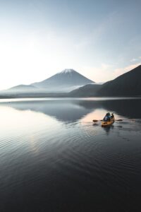yellow kayak on calm water near mountain during daytime